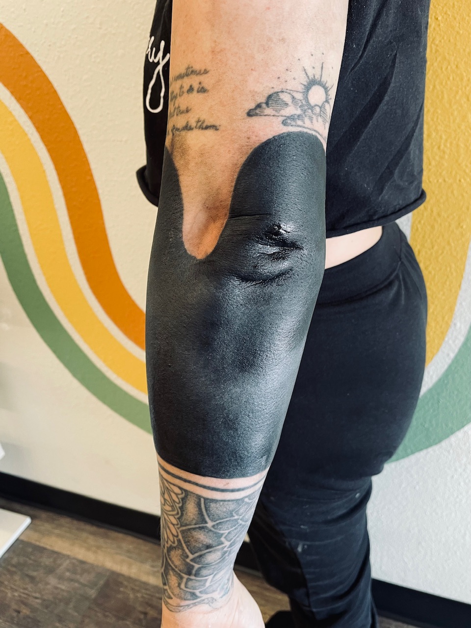 Blackwork arm tattoo looks like a wave or mountains